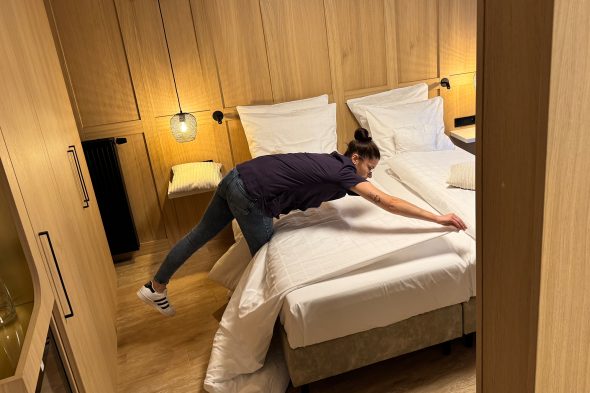 Mitarbeiterin macht das Bett in einem Hotelzimmer im Bütgenbacher Hof