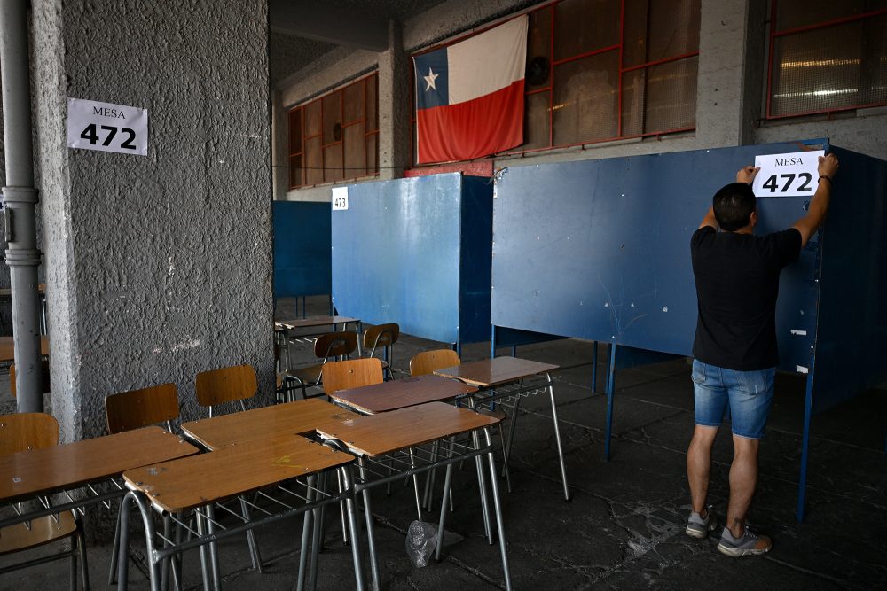 ein Mann hängt Nummern der Wahlbüros an die Wände, im Vordergrund Tische