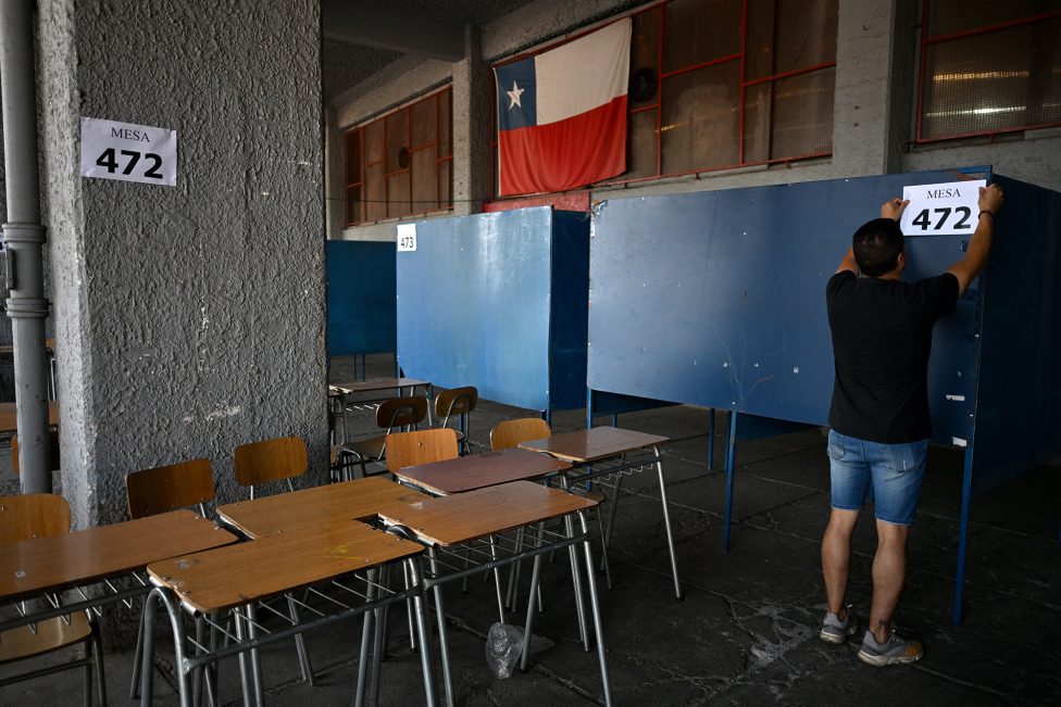 ein Mann hängt Nummern der Wahlbüros an die Wände, im Vordergrund Tische