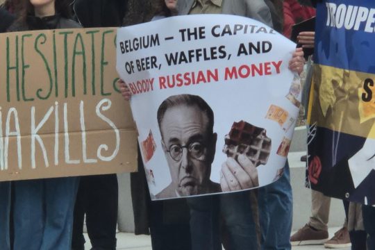 Demo in Brüssel - auf dem Plakat steht "Belgien, die Hauptstadt von Bier, Waffeln und blutigem russischem Geld"