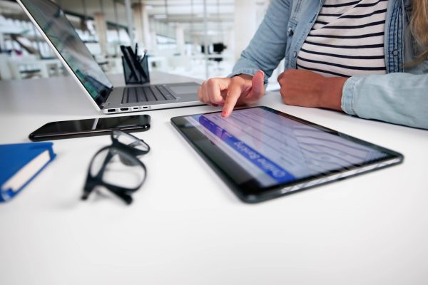 Eine Frau am Schreibtisch mit Laptop und Tablet