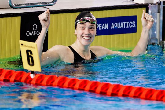Florine Gaspard im Schwimmbecken, sie hebt jubelnd die Hände in die Höhe