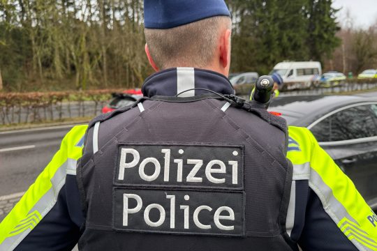 Schriftzug "Polizei - Police" auf dem Rücken eines Polizisten bei einer Kontrolle