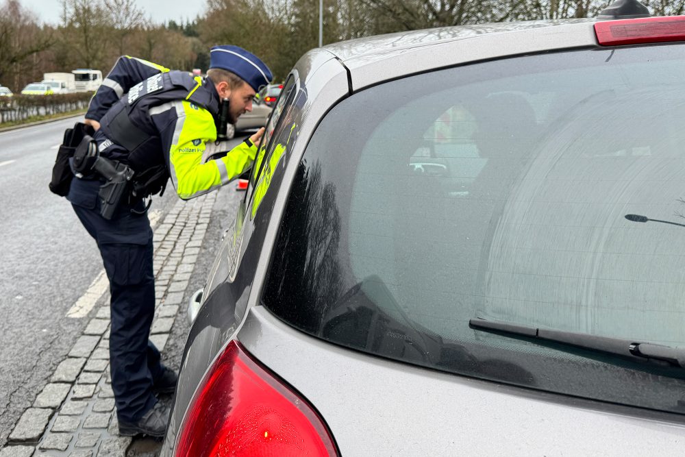 Polizist der Zone Eifel schaut in ein Auto bei der Bob-Kontrolle an der belgisch-luxemburgischen Grenze in der Nähe des Kreisverkehrs Wemperhardt