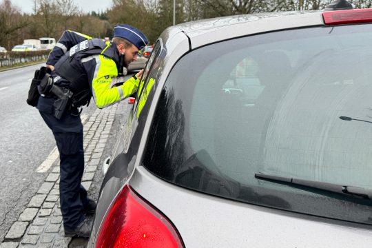 Polizist der Zone Eifel schaut in ein Auto bei der Bob-Kontrolle an der belgisch-luxemburgischen Grenze in der Nähe des Kreisverkehrs Wemperhardt