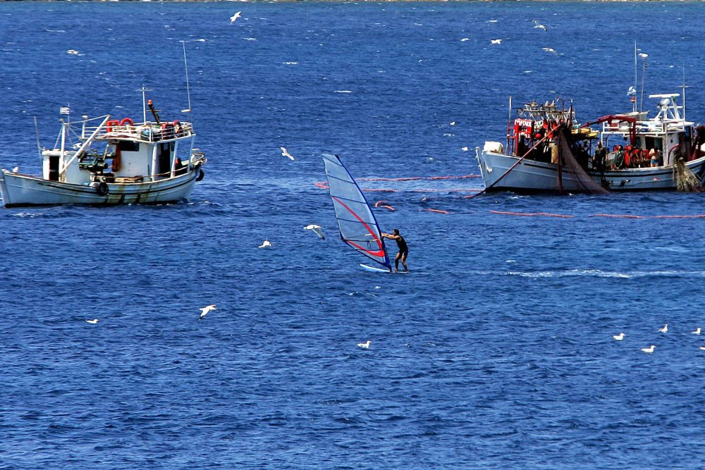 zwei Fischerboote, ein Windsurfer auf dem Wasser