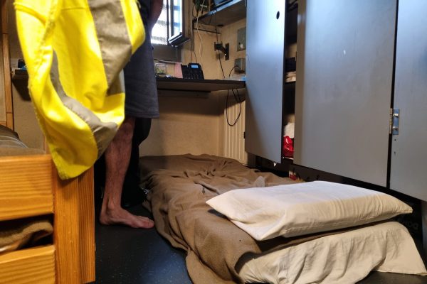 Zelle mit einem Hochbett vor den Schränken liegt eine weitere Matratze auf dem Boden
