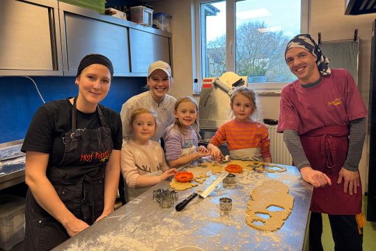 Kinder und Mitarbeiter des Hof Peters vor dem Arbeitstisch mit dem Plätzchenteig darauf