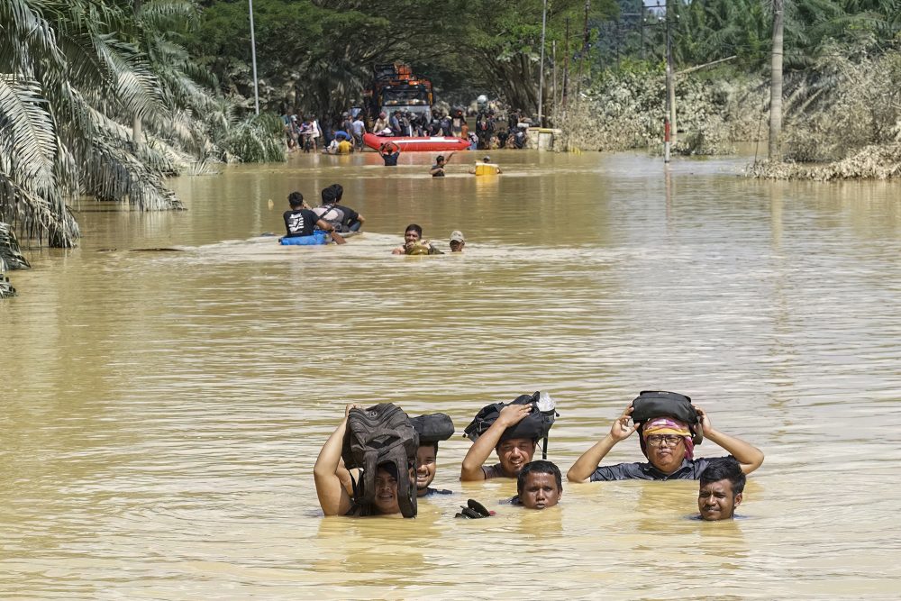 Mehreren Menschen steht das Wasser buchstäblich bis zum Hals, sie halten in der völlig überfluteten Straße ihre Habseligkeiten über ihren Köpfen