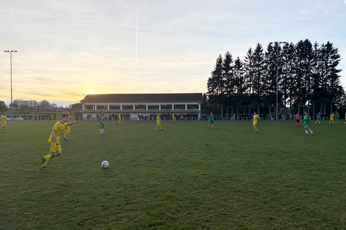 Spieler auf dem Platz bei der Partie Weywertz vs Amel bei Sonnenuntergang