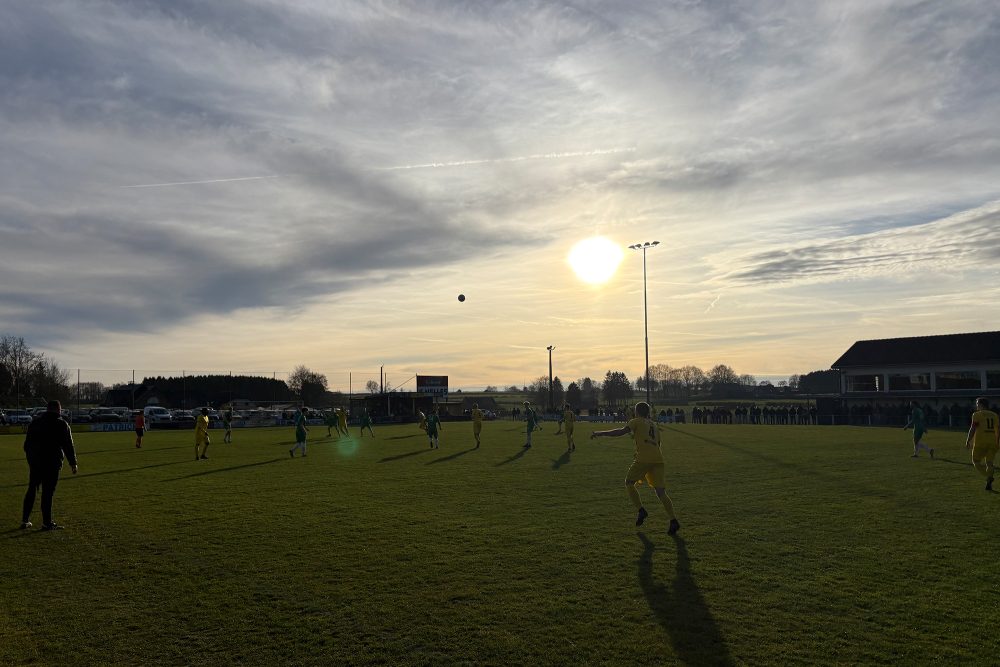 Spieler auf dem Platz bei der Partie Weywertz vs Amel bei Sonnenuntergang
