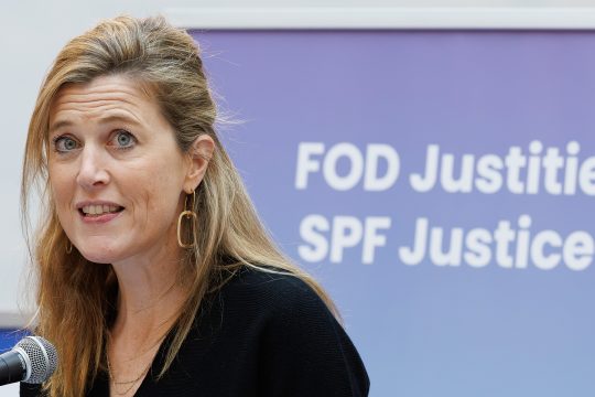 Annelies Verlinden am Rednerpult vor einem Banner mit der Aufschrift "Föderaler Öffentlicher Dienst Justiz"