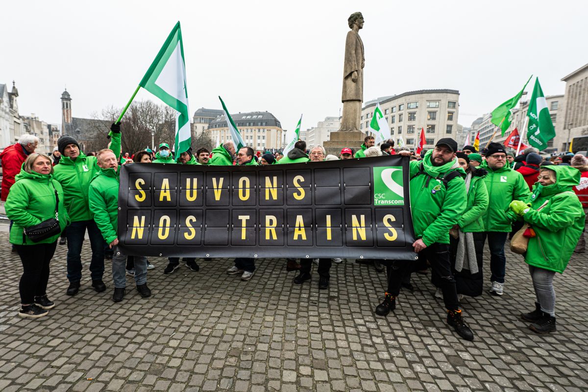 Streikende Bahnbeschäftigte vor dem Brüsseler Hauptbahnhof halten ein Transparent hoch mit der Aufschrift, auf Deutsch übersetzt, "Rettet unsere Züge"