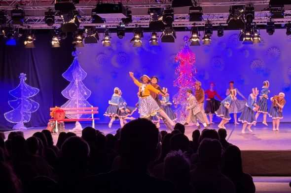 Balletttänzer auf der Bühne während der Aufführung, vorne im Bild die Umrisse des Publikums von hinten