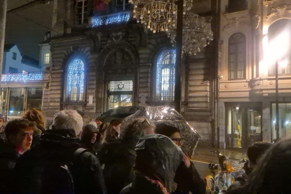 Menschengruppe steht im Regen vor dem Brüsseler Parlament