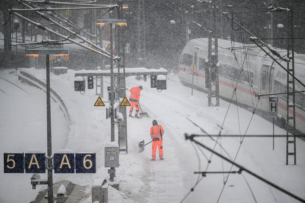 Arbeiter räumen Schnee auf den Gleisen und Bahnsteigen im Hauptbahnhof Hamburg
