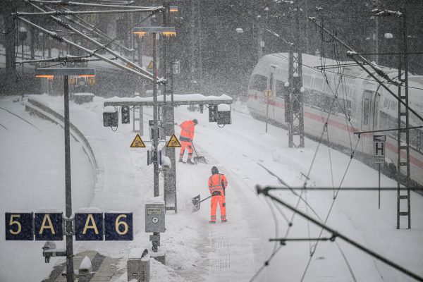 Arbeiter räumen Schnee auf den Gleisen und Bahnsteigen im Hauptbahnhof Hamburg