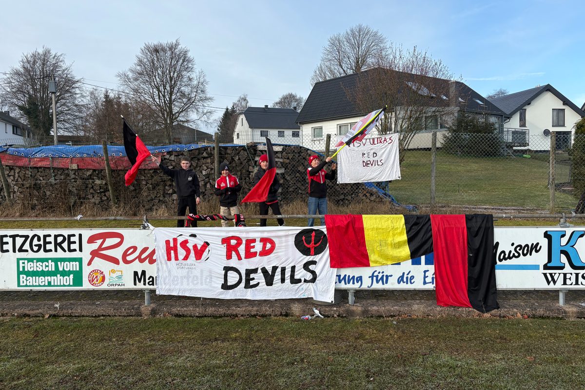 Fans des Honsfelder SV am Spielfeldrand schwenken Fahnen