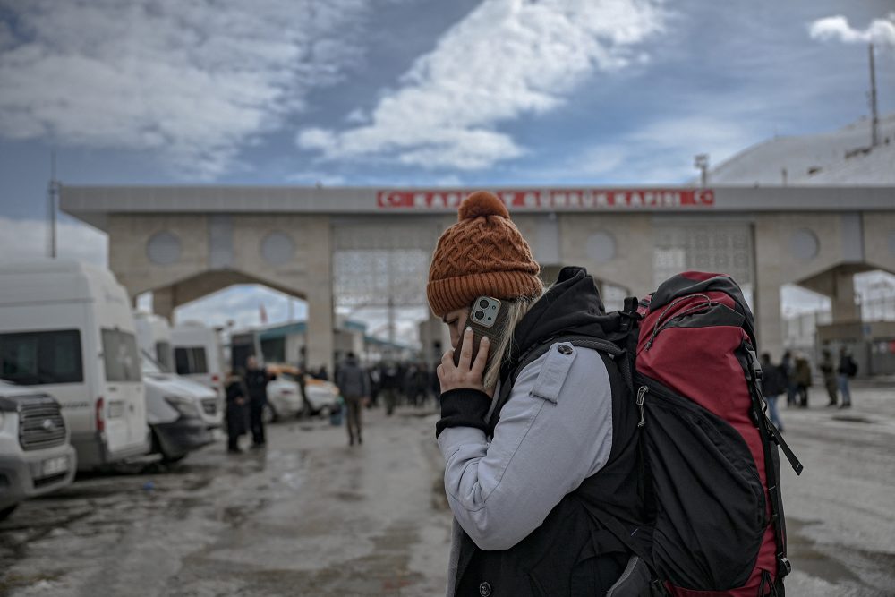 Eine iranische Frau telefoniert, während sie mit ihrem Rucksack auf einen Minibus wartet