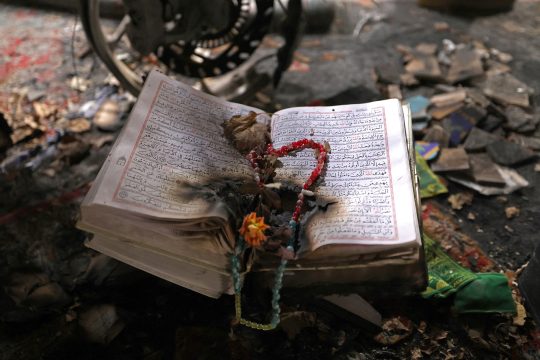 Verbrannte religiöse Bücher, darauf Gebetsperlen und eine Blume