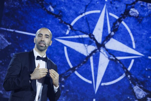 Sammy Mahdi beim CD&V-Neujahrsempfang, hinter ist ihm ist das Bild eines rissigen Nato-Symbols dargestellt