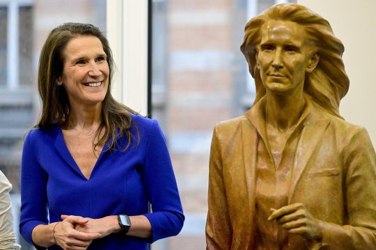 Sophie Wilmès steht lachend neben ihrer Büste