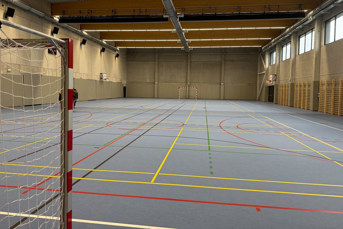 Im Inneren der Sporthalle, auf dem Boden sind in unterschiedlichen Farben die jeweiligen Spielfeldbegrenzungen markiert