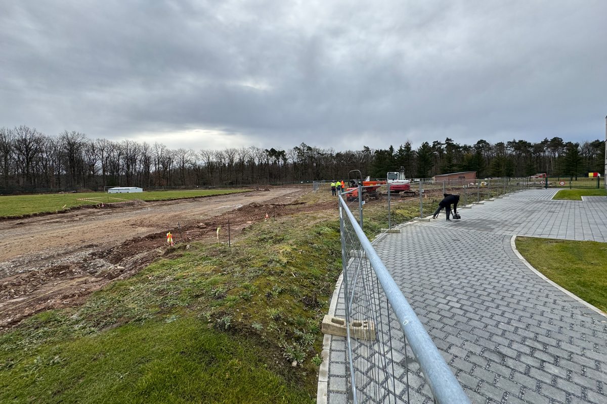 Arbeiter führen auf einem Fußweg und auf dem Gelände, auf dem die Laufbahn entsteht, Arbeiten durch