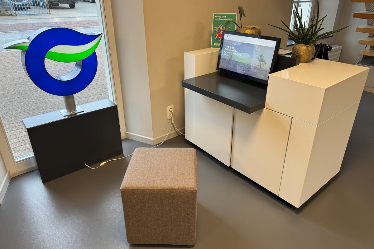 Ein Computerbildschirm zeigt Informationen für die Touristen an, davor ein Würfel als Sitzgelegenheit