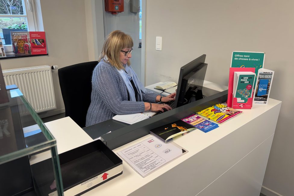 Mitarbeiterin am Empfang des Tourist-Info-Büros arbeitet am Laptop