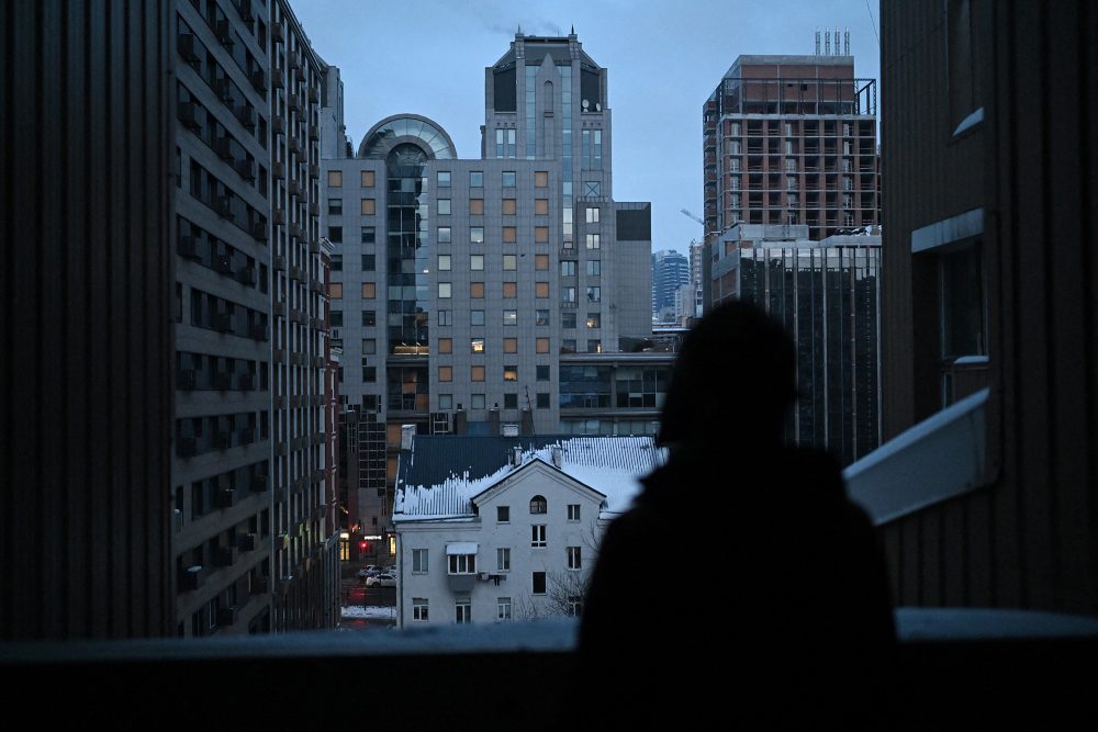 Die 67-jährige ukrainische Künstlerin Oksana Gordiets blickt am 25. Januar 2026 in Kiew von ihrem Balkon auf ein Gebäude, dessen Fenster durch Beschuss zerbrochen sind.