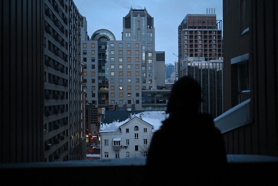 Die 67-jährige ukrainische Künstlerin Oksana Gordiets blickt am 25. Januar 2026 in Kiew von ihrem Balkon auf ein Gebäude, dessen Fenster durch Beschuss zerbrochen sind.