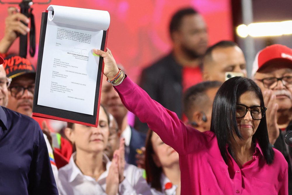 Die venezolanische Interimspräsidentin Delcy Rodriguez steht vor dem Präsidentenpalast in Caracas und hält eine Kopie des Gesetzes hoch