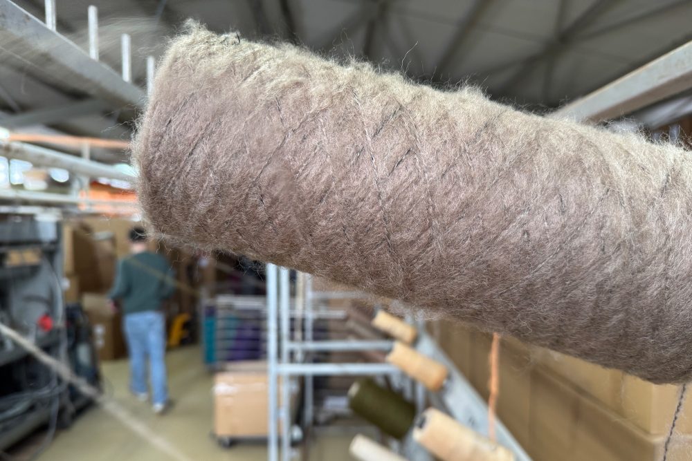 Eine große Spule hängt an der Knäuelwickelmaschine