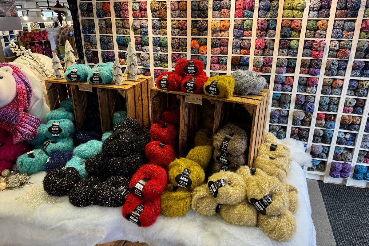 Wollknäuel in diversen Farben liegen für die Kunden im Laden aus