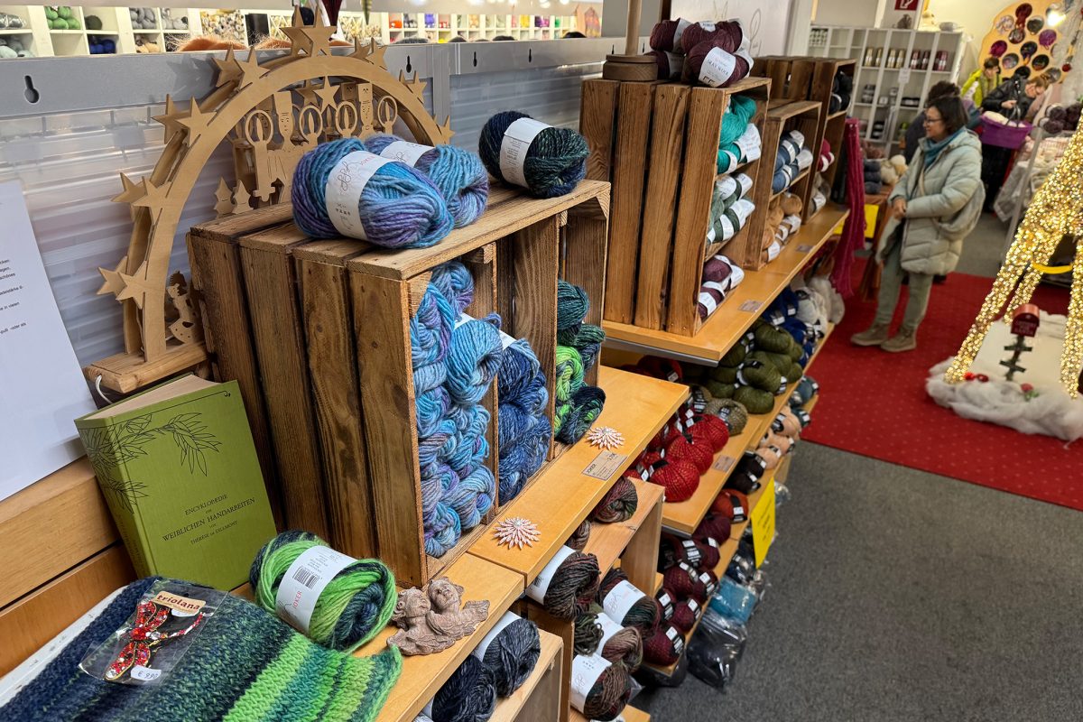 Wollknäuel in diversen Farben liegen für die Kunden im Laden aus