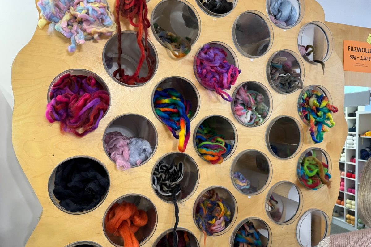 Wollknäuel in diversen Farben liegen für die Kunden im Laden aus