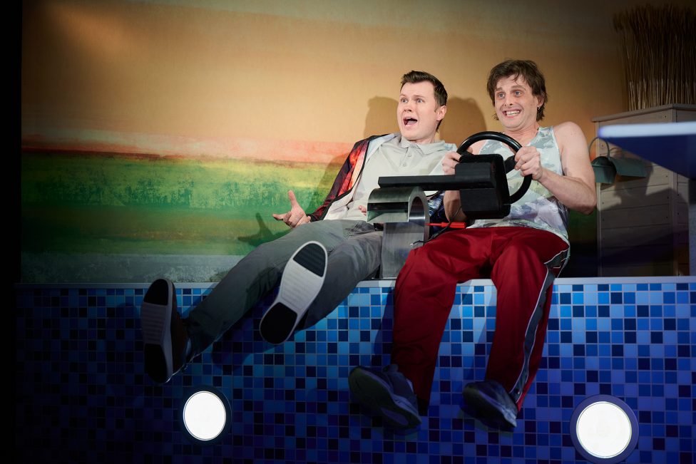 Szene aus dem Theaterstück "Tschick" im Das-da-Theater: Die beiden Hauptfiguren sitzen auf der Bühne, einer hält ein Lenkrad in den Händen