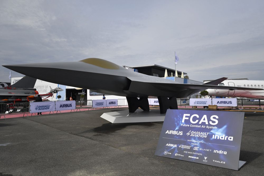 Das Modell eines Kampfjets, davor ein Schild mit der Aufschrift FCAS und den Logos der beteiligten Firmen Dassault Aviation, Airbus und Indra Sistemas