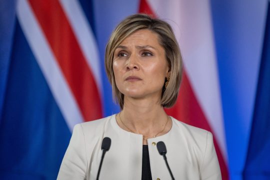 Die isländische Premierministerin Kristrun Frostadóttir steht an einem Rednerpult, im Hintergrund gibt es isländische Flaggen