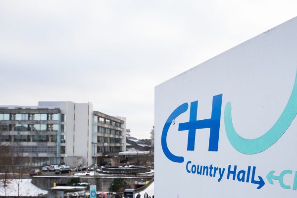 Im Vordergrund ein Hinweisschild mit der Aufschrift CHU, im Hintergrund einer der charakteristischen Türme der Uniklinik CHU