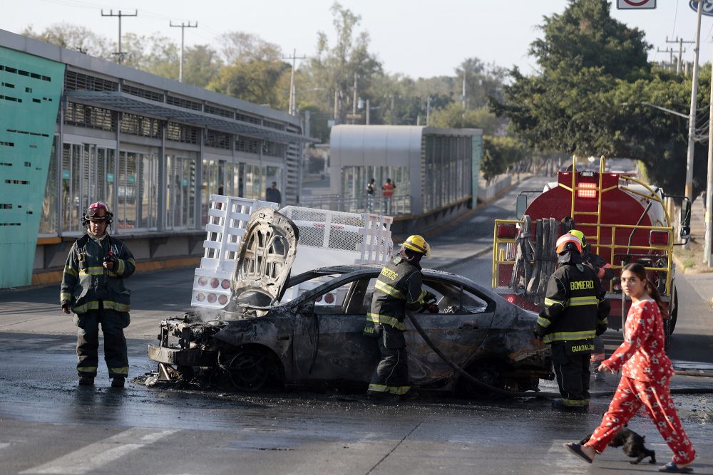 Feuerwehrleute löschen ein brennendes Auto