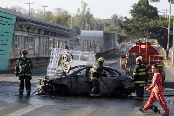 Feuerwehrleute löschen ein brennendes Auto