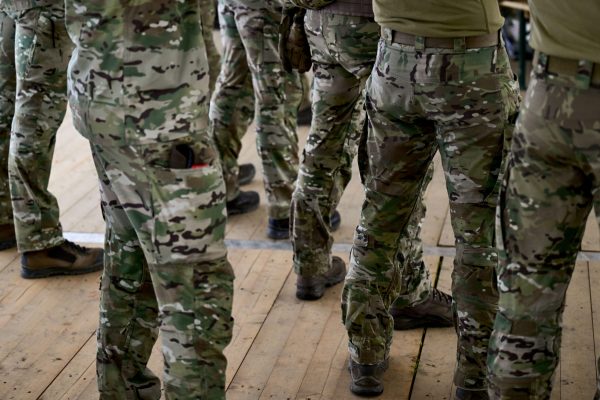 mehrere Nato-Soldaten in Tarnuniform stehen abwartend beisammen