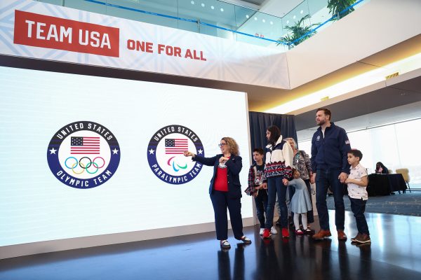 US-Vizepräsident JD Vance steht mit seiner Familie vor dem Banner, das die Aufschrift "Team USA - One for all", die amerikanische Flagge und die Olympischen Ringe zeigt