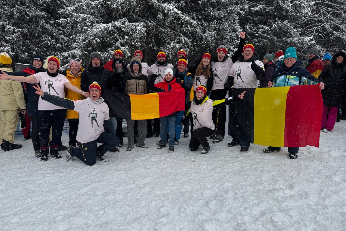 Ostbelgische Fans mit Mützen in den belgischen Farben und belgischen Flaggen stehen im Schnee an der Strecke