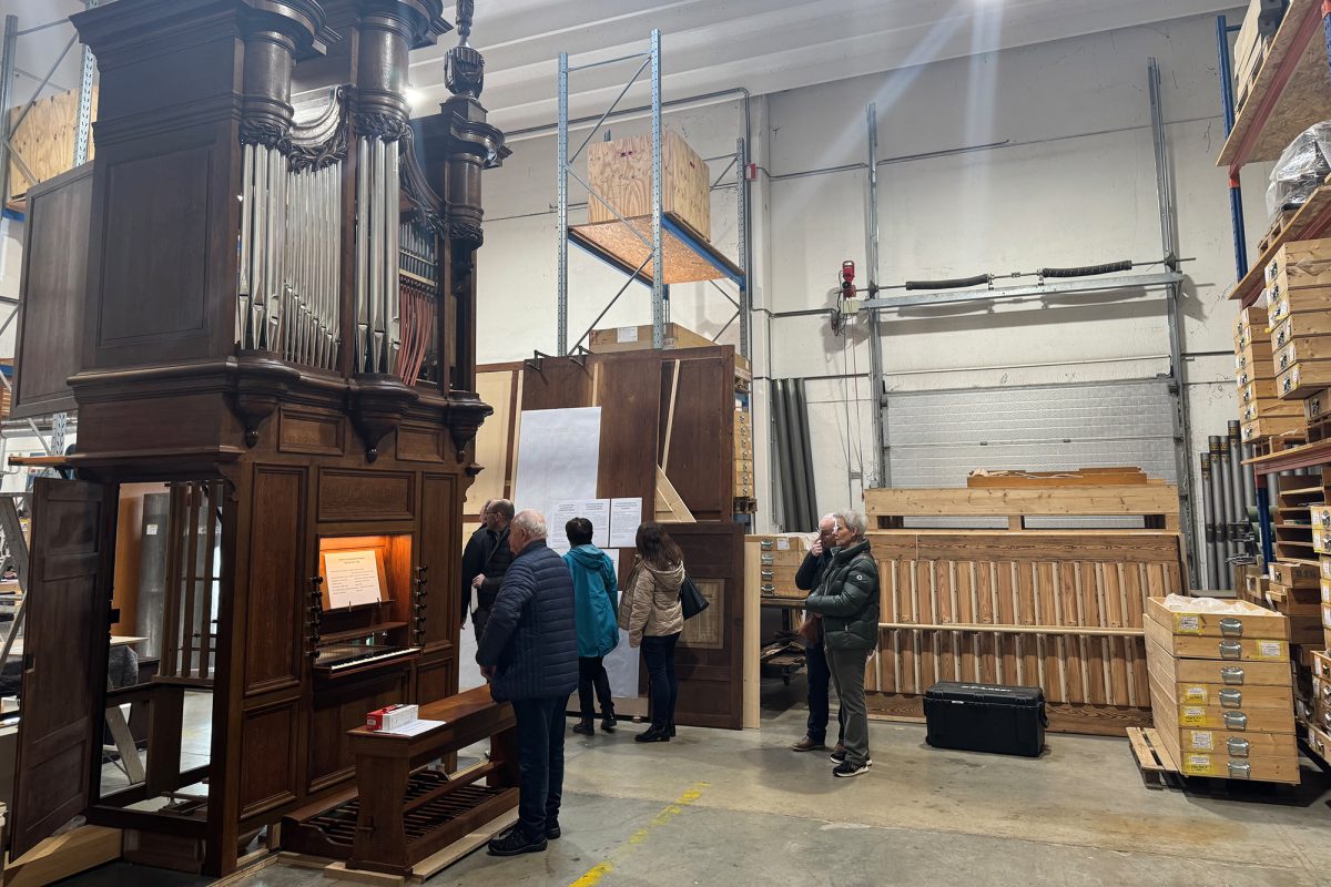 Besucher beim Tag der offenen Tür in der Produktionshalle, in der eine Orgel und mehrere Hochregale stehen