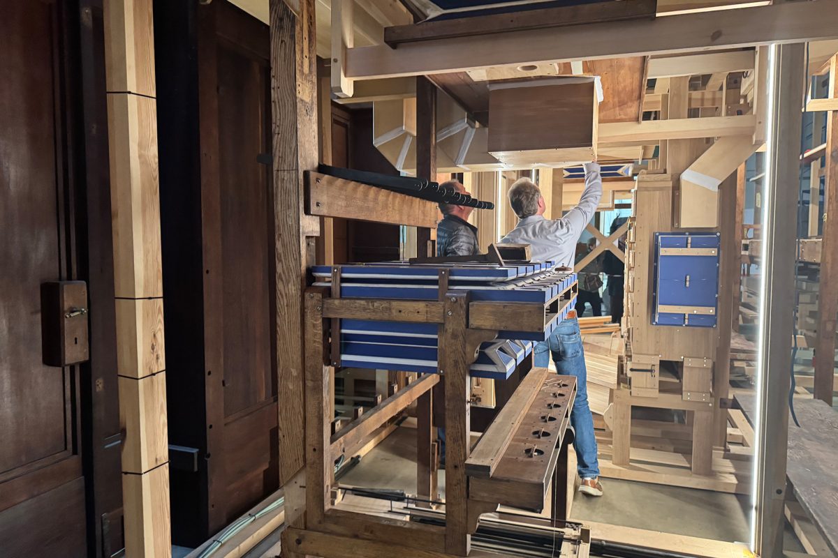Holzgerüst einer Orgel, zwei Menschen von hinten schauen nach oben