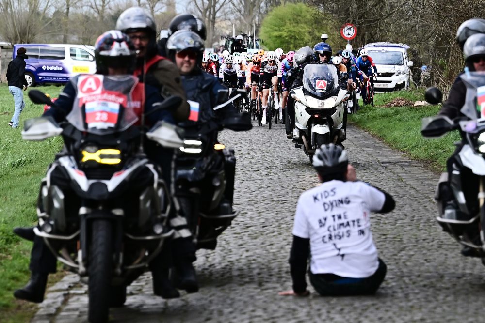 Klimaaktivist sitzt auf dem Boden bei der Radrundfahrt von Brügge