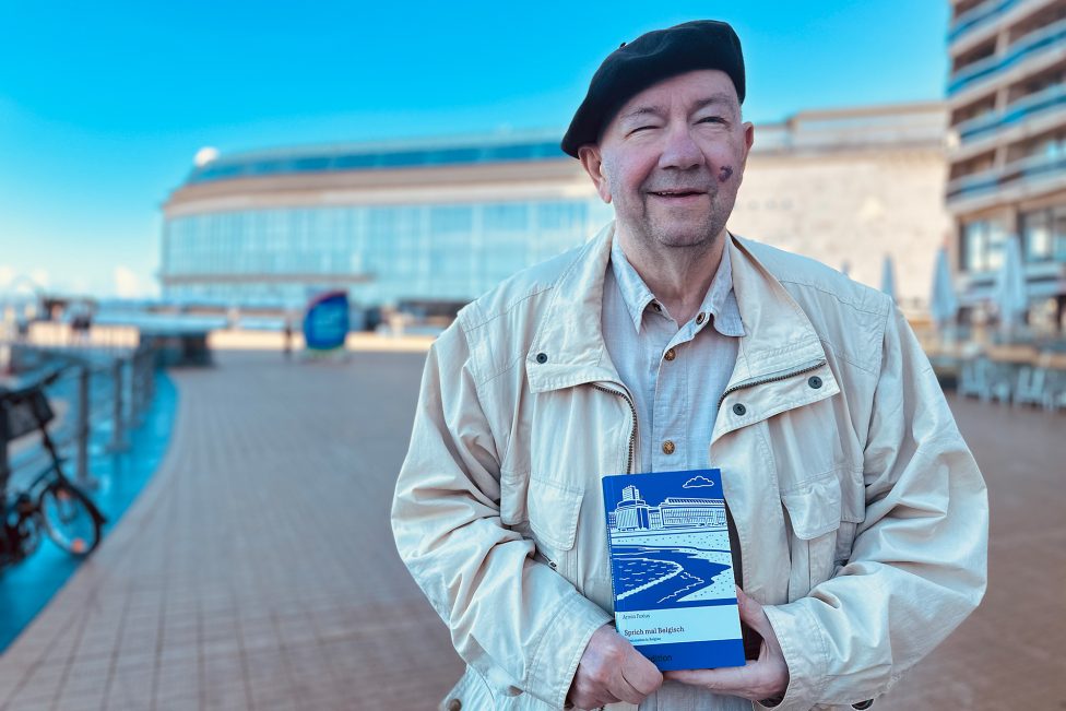 Armin Foxius hält sein Buch in den Händen und lächelt in die Kamera